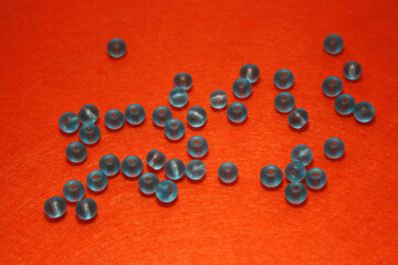 Blue beads on the orange felt background.