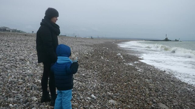 CTS1 Child Throwing Stone in Stormy Sea. Waves Crashing on Pebble Beach. Atlantic Ocean. Grey Overcast Sky. English Channel. France Europe. 2x Slow motion 60 fps 4K