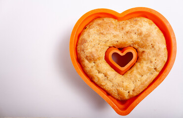 Fruitcake baked in the shape of a heart on a white background with space for text.