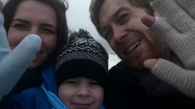 Happy Family Taking Selfie Pictures Video in Front of Stormy Sea. Waves Crashing on Pebble Beach. Slow motion