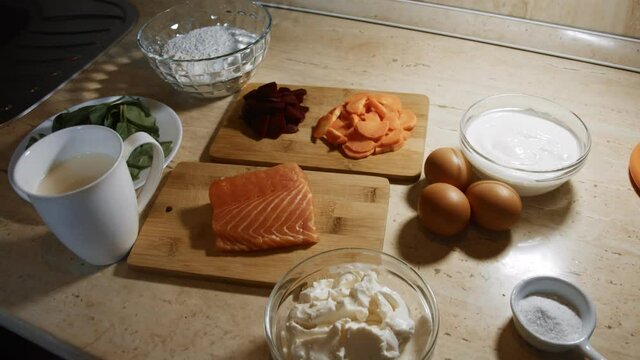 Thin tasty colorful pancakes. Top view of ingredients for preparing red, yellow and green rolled pancakes with cream cheese and salmon filling. 4K video.