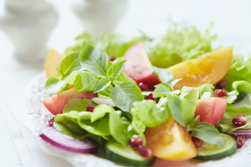 Salad with red and yellow Tomatoes and Pomegranate Seeds on bright wooden Background. Close up.