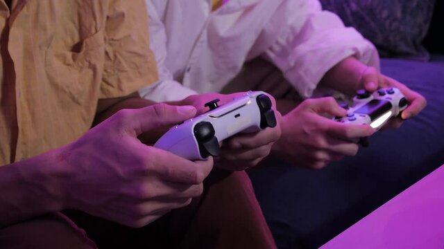 Close view of a gamers hands playing video games on console using joystick.