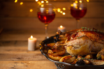 Tasty appetizing baked turkey with potato on wine glasses and candles background. Concept of festive Christmas dinner.