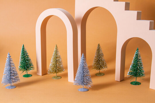 A surreal Christmas, shiny Christmas trees stand in a row under the paralon arches, an unusual background.

