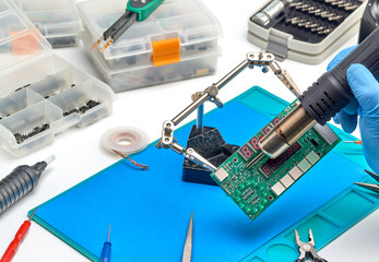 The master in the service center repairs the electronic unit.A soldering iron and a blow dryer heat the soldering parts.