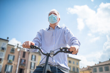 Man riding his bike in a city while wearing a covid coronavirus mask