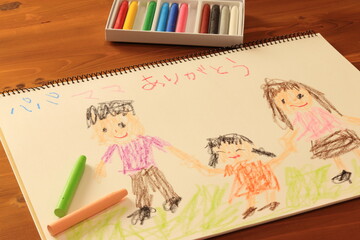 クレヨンでスケッチブックに描かれた家族の絵