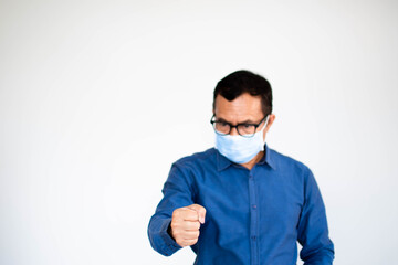 A young male is standing and his fist clenched in anger. One man at home wearing a face mask to prevent coronavirus drainage or covid-19, Close up photo, and selective focus on hand. White background.