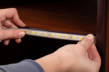 master installs led strip on the shelf close-up