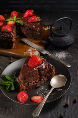 chocolate cake with strawberries on a black plate