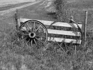 Fototapeta na wymiar A horizontal photo of old wagon wheels leaning on a wooden gate.