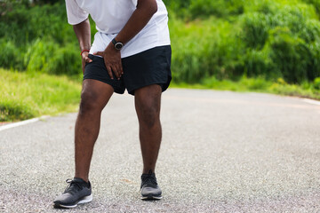 Close up Asian young sport runner black man wear watch hands joint hold leg she has thigh pain...