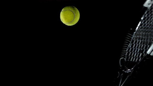 Super slow motion of dribbling tenis ball with rocket on black background. Filmed on high speed cinema camera, 1000fps.