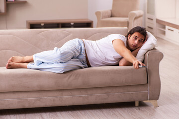 Young lazy man in oversleeping concept at home