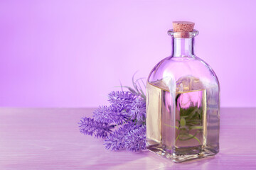 Obraz na płótnie Canvas A bottle of essential oil with fresh blooming lavender twig on table with copy space. Aromatherapy spa massage concept.