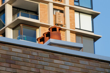 Detail of 3 old style terracotta-colored ventilation hoods on suburban roof. Full frame