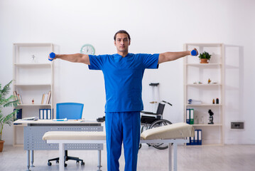 Young male doctor physiotherapist doing sport exercises