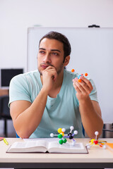 Young male student physicist studying molecular model at home