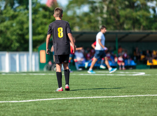 Boys in black sportswear plays football on field, dribbles ball. Young soccer players with ball on green grass. Training, football, active lifestyle for kids
