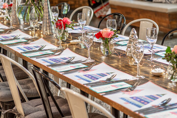 A long table set up for Christmas dinner with placemats, cutlery, glasses and flowers