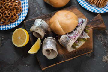 Rustic wooden serving board with fischbrotchen or german traditional fish sandwich, elevated view on a brown stone background