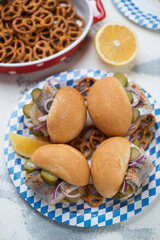 Blue and white carton plate with fischbrotchen or german traditional fish sandwiches, vertical shot on a white concrete background