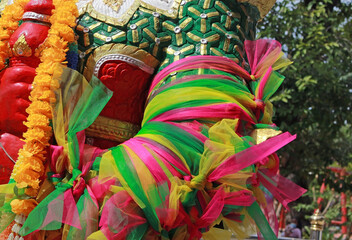 Fototapeta na wymiar Close-up detail of colorful ribbons tied around the arm of a statue at a Buddhist temple in southeast Asia