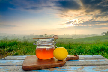 Alternative Medicine with lemon  and  honey on wooden table. Beautiful sunrise as background.