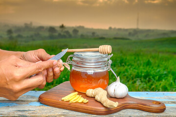 Man's hands cutting fresh garlic  with beautiful sunrise as background.