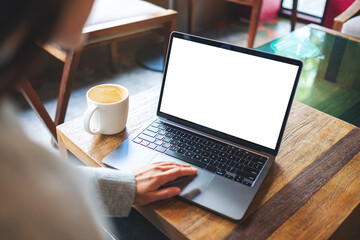 Mockup image of a woman using and touching on laptop touchpad with blank white desktop screen in cafe