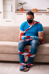 Obraz premium Young man watching tv at home in pandemic concept
