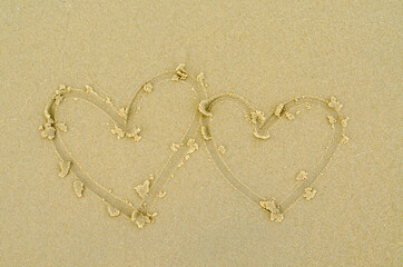 hand drawing two hearts on the sand