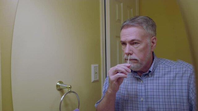 A man taking a nasal swab as part of a home self-test kit to determine if he has SARS-CoV-2 virus better known as COVID 19.