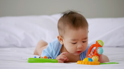 Adorable little baby playing a toy on bed.