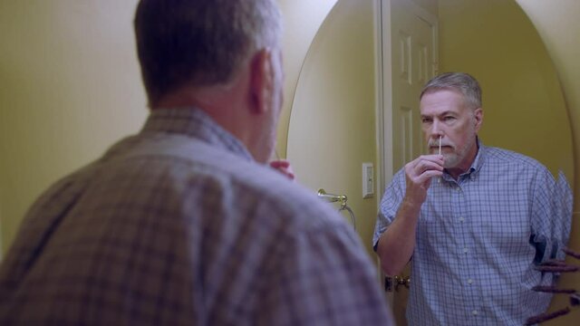Nasal swabbing as part of a home self-test kit to determine if SARS-CoV-2 virus better known as COVID 19 will be detected being self administered by this mature gentleman.
