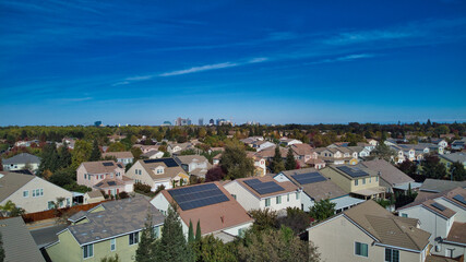 Suburban homes with solar panels with downtown high rise buildings in the distance  - obrazy, fototapety, plakaty