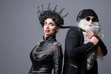 Dj Santa Claus with Sunglasses and Headphones Listening to Christmas Music and Snow Maiden Black Leather Jacket Having Fun. Rock Party Time. Studio Shot Over Grey Background.