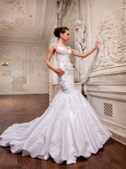 Fototapeta na wymiar Beautiful bride in a white wedding dress in a light old classic interior