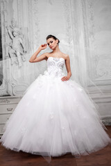 Beautiful bride in a white wedding dress in a light old classic interior