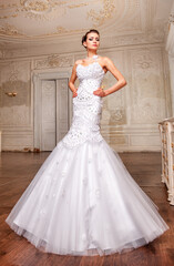 Beautiful bride in a white wedding dress in a light old classic interior