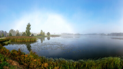 rare landscape with a rainbow of fog in the early autumn morning, lake shore, traditional lake meadow vegetation in the foreground, autumn colors in nature, Lielais Ansis, Rubene, Latvia