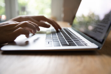 Close up female hands typing on laptop keyboard, writing email or report, browsing apps,...