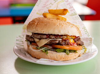 Juicy double cheeseburguer with bacon, tomato, salad and sauces.