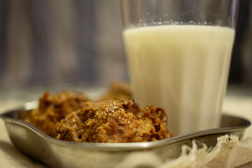 View of crunchy coconut cookies along with hot milk in a glass.