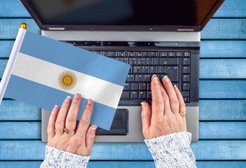 woman hands and flag of Argentina on computer, laptop keyboard 