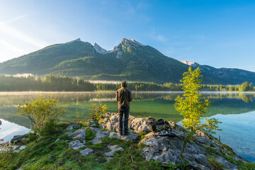 Man overlooking hintersee lake at sunrise. Bavarian Alps on the Austrian border, Germany, Europe