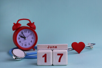 June 17st. White wooden calendar blocks with date, clock and stethoscope on a blue pastel background. Selective focus. health concept