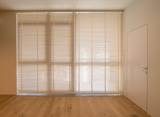 Motorized wood blinds in the interior. Automatic venetian blinds beige color on large windows....