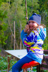 Adorable happy kid spending leisure time at playground. Outdoor shot of carefree preteen girl in blue jacket and jeans. Active weekend outside.